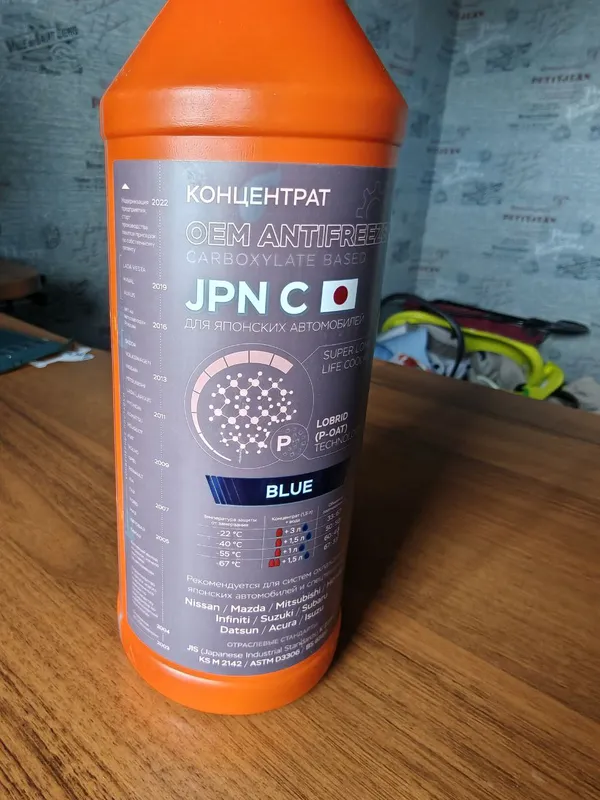 Оранжевая бутылка концентрата Coolstream JPN C Blue с выцветшей серой этикеткой на столе