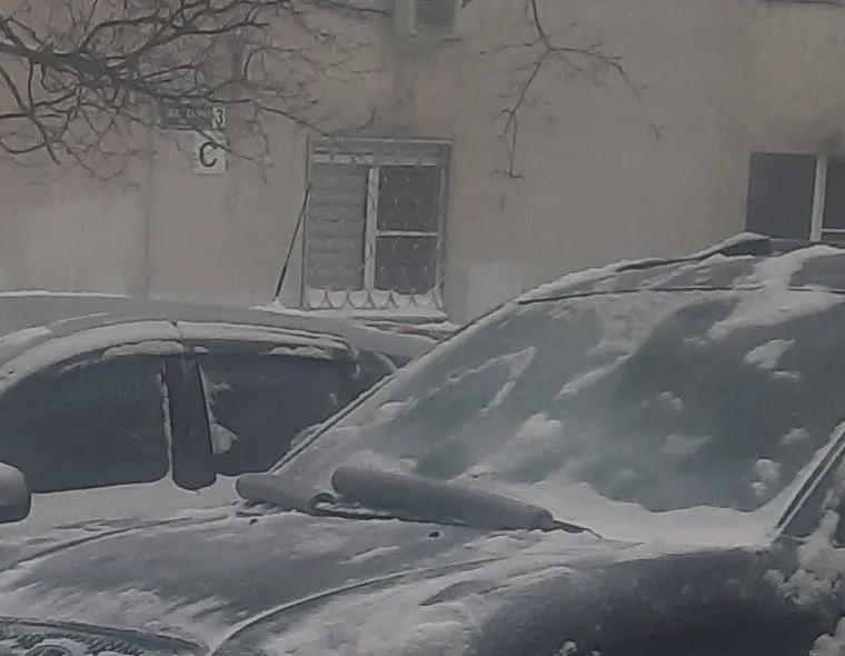 Обе щетки дворников надеты в серые трубки утеплителя, машина под снегом