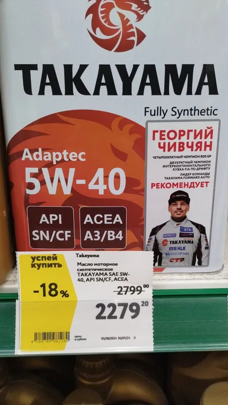 Канистры Takayama Adaptec 5W-40 на полке магазина, на ценнике 2279 рублей со скидкой 18%