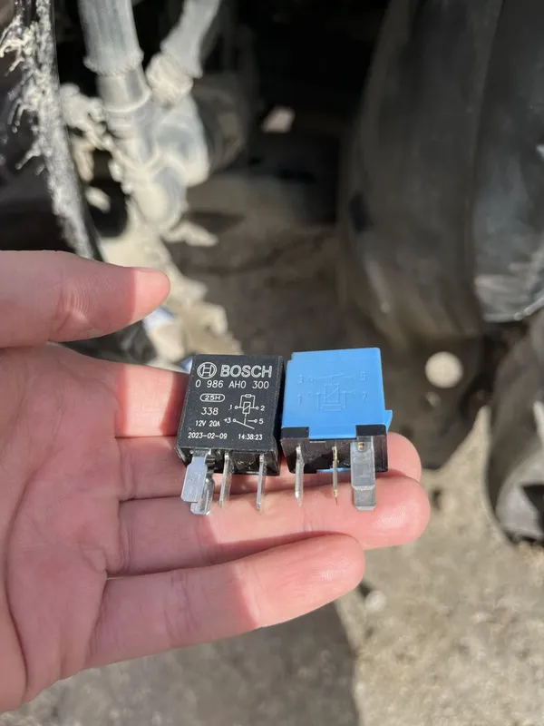 Реле Bosch 0 986 AH0 300 на 12 В 20 А рядом с синим ниссановским реле на ладони
